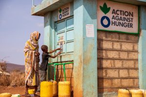 A mom and her child filling up their jerrycan with water at a local action against hunger water station in kenya