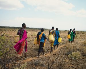 A family carrying jerrycan's filled with water on their long walk home across a plain impacted by drought in kenya