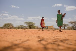 two masaai women walking through a dry plain impacted by the droughts in kenya