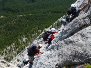 A line of hikers climbing up a steep rock mountain