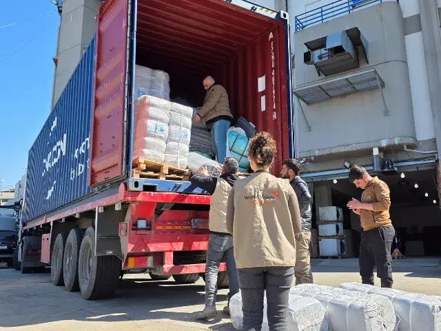 A container truck carrying provisions and people unloading the provisions - Humanitarian Coalition